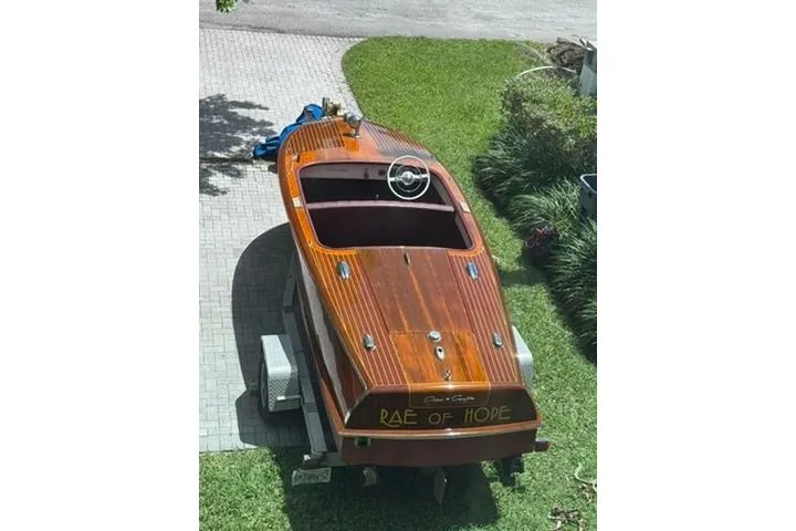 Slide: The Image of 1952 Chris-Craft 18 Runabout boat on trailer, named "Rae of Hope," parked on grass. - 35