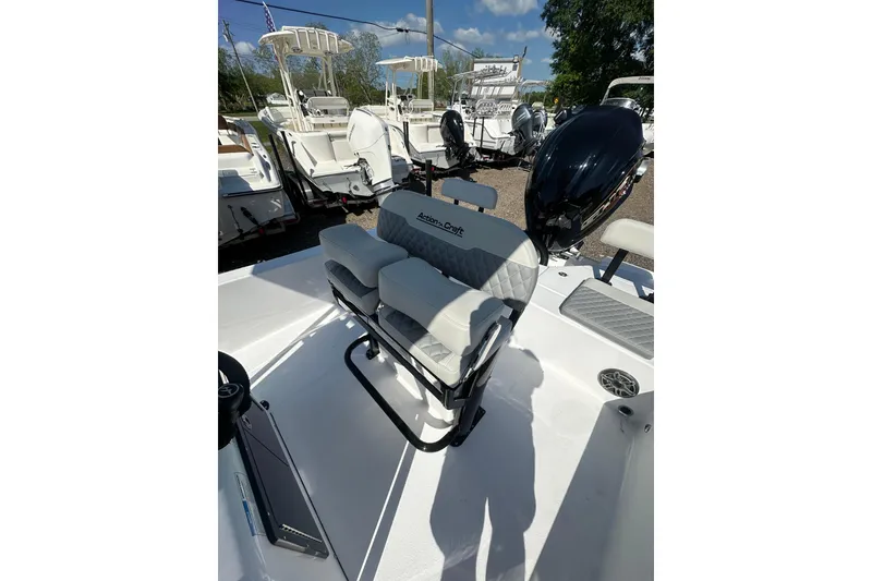 Slide: The Image of 2026 Action Craft 22 Bay boat interior with cushioned seating and motor, parked outdoors. - 18