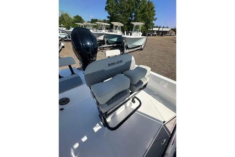 Slide: The Image of 2026 Action Craft 22 Bay boat with cushioned seating and outboard motor in a sunny marina. - 20