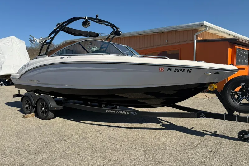 The Image of 2023 Chaparral 23 SSi boat on trailer, parked outdoors near an orange building. - 0