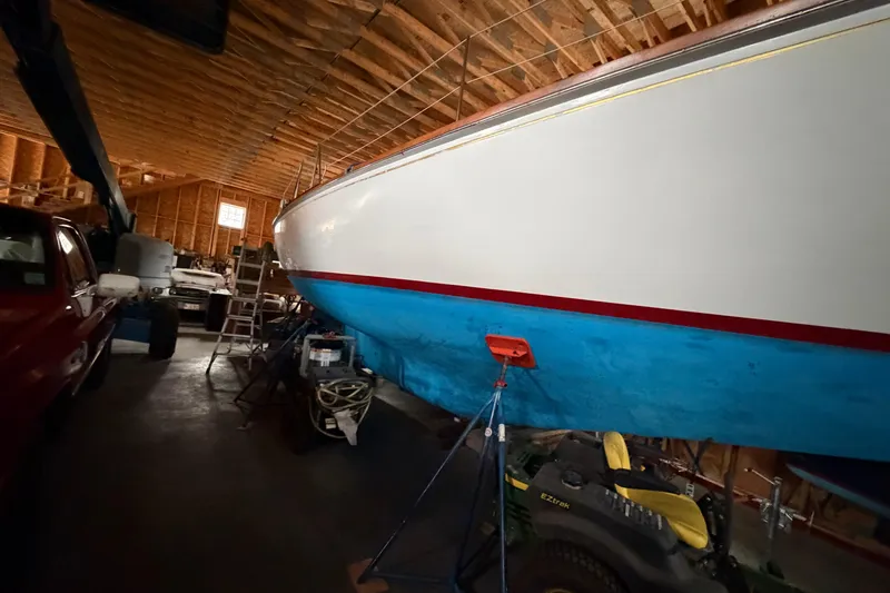 Slide: The Image of 1963 Hinckley Bermuda 40 sailboat in a wooden garage, partially visible with blue hull. - 57