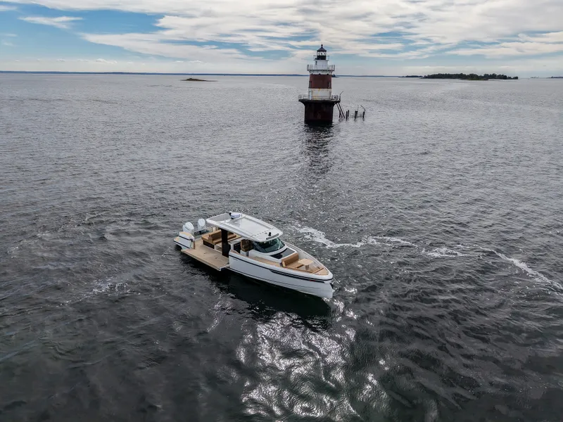 Slide: The Image of A 2027 Saxdor 400 GTS boat cruising near a lighthouse on calm waters. - 34