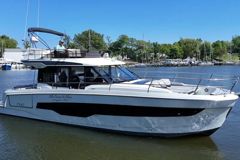 Slide: The Image of 2024 Jeanneau NC Weekender 1295 Fly boat on calm water, with a person on deck. - 1