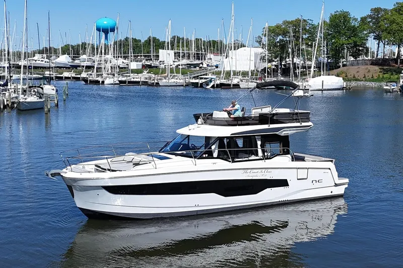 Slide: The Image of 2024 Jeanneau NC Weekender 1295 Fly yacht in a marina, surrounded by sailboats. - 2