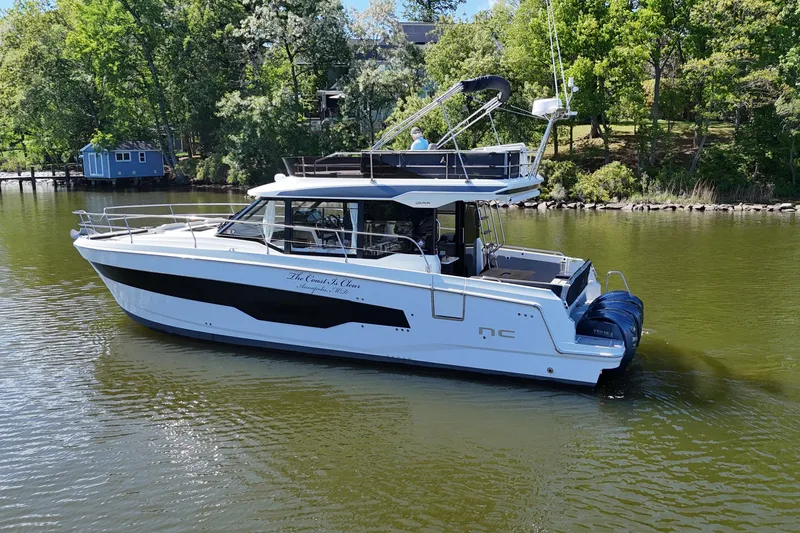 Slide: The Image of 2024 Jeanneau NC Weekender 1295 Fly cruising on a serene lake with lush greenery. - 4