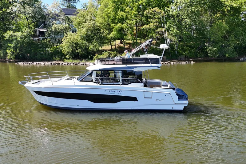 Slide: The Image of 2024 Jeanneau NC Weekender 1295 Fly with people relaxing on deck in calm waters. - 7