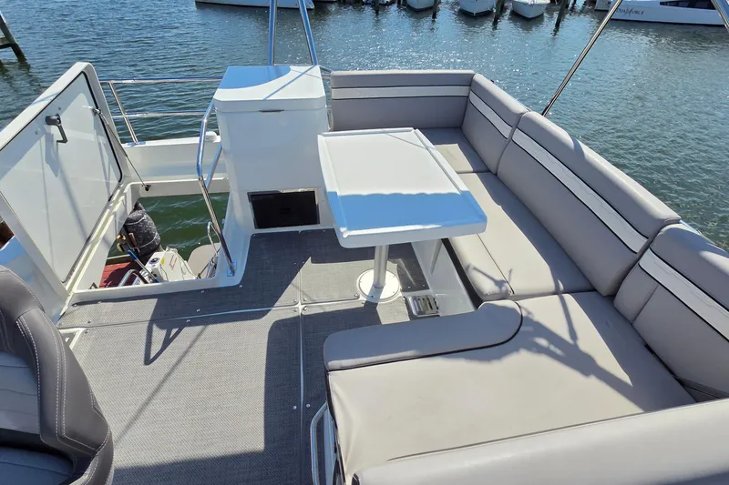Slide: The Image of 2024 Jeanneau NC Weekender 1295 Fly boat deck with seating and table, docked by water. - 9