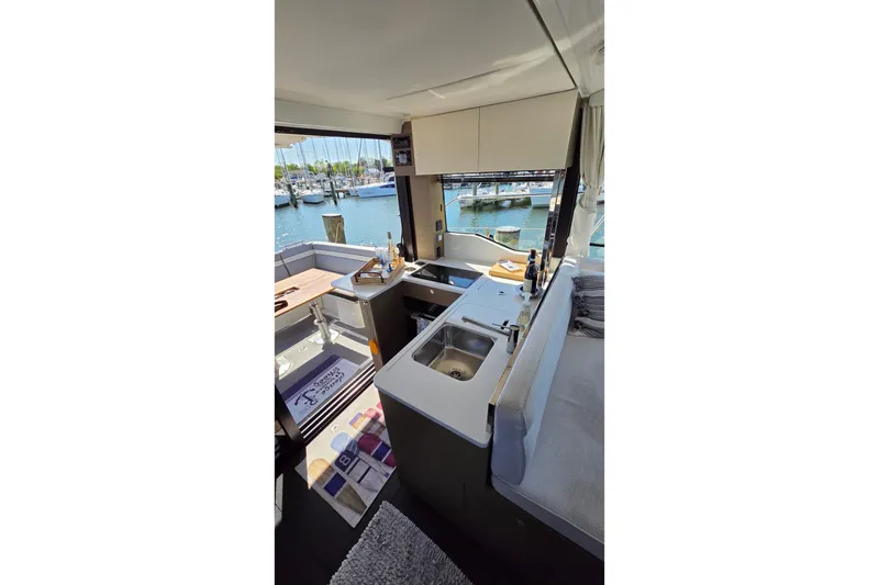 Slide: The Image of Interior view of 2024 Jeanneau NC Weekender 1295 Fly, featuring a modern kitchen and marina backdrop. - 12