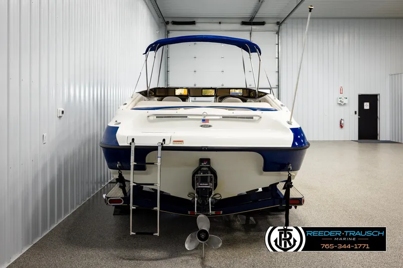 Slide: The Image of 2001 Crownline 225 BR boat in indoor storage, rear view with blue and white design. - 7