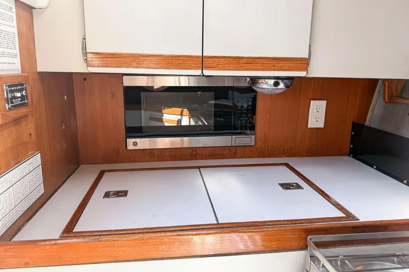 Slide: The Image of 1988 Oday 40 yacht galley with microwave, wooden cabinetry, and white countertop. - 21