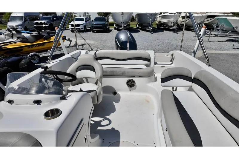 Slide: The Image of 2016 Starcraft 2000 Sportstar boat interior with seating and steering wheel, parked near other vehicles. - 14