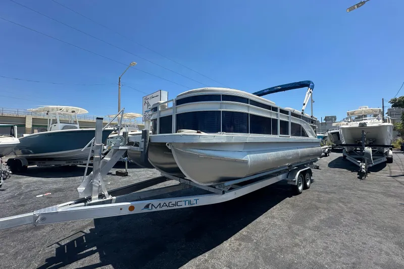 The Image of 2016 Bennington 21 SX L-Bench pontoon boat on trailer in sunny marina. - 0