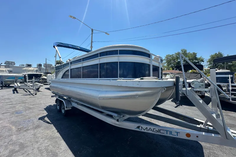 Slide: The Image of 2016 Bennington 21 SX L-Bench pontoon boat on Magic Tilt trailer under clear blue sky. - 5
