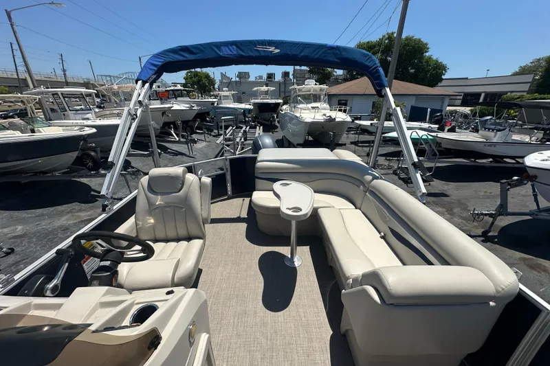 Slide: The Image of 2016 Bennington 21 SX L-Bench pontoon boat with seating and canopy in a marina. - 8