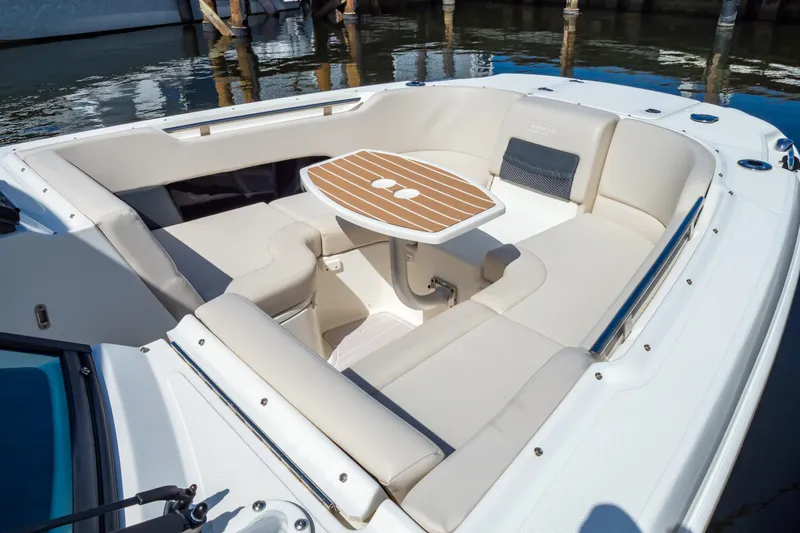 Slide: The Image of 2019 Boston Whaler 270 Vantage boat interior with cushioned seating and wooden table. - 2