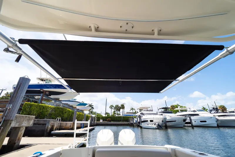 Slide: The Image of 2019 Boston Whaler 270 Vantage with sunshade, docked at marina with yachts. - 34