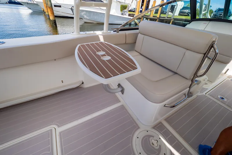 Slide: The Image of 2019 Boston Whaler 270 Vantage interior with seating and table, docked by the water. - 37