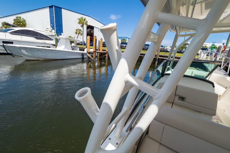 Slide: The Image of 2019 Boston Whaler 270 Vantage docked near marina, showcasing sleek design and rod holders. - 38