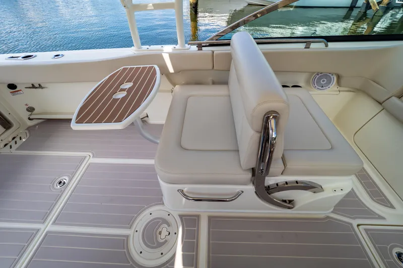 Slide: The Image of 2019 Boston Whaler 270 Vantage boat interior with seating and table, docked by water. - 39