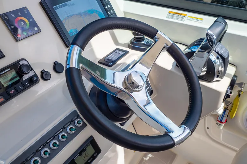 Slide: The Image of Steering wheel and controls of a 2019 Boston Whaler 270 Vantage boat cockpit. - 48