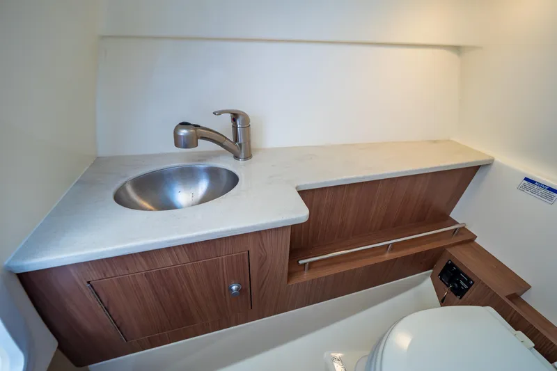 Slide: The Image of 2019 Boston Whaler 270 Vantage boat bathroom with sink and wooden cabinetry. - 77