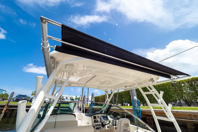 Slide: The Image of 2019 Boston Whaler 270 Vantage boat with canopy, docked under clear blue sky. - 92