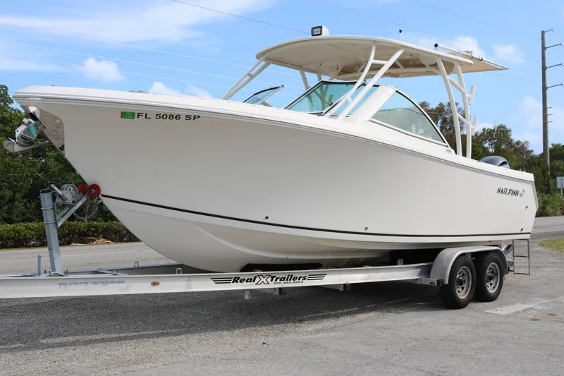 The Image of 2020 Sailfish 275 DC boat on trailer, parked outdoors under a clear blue sky. - 1