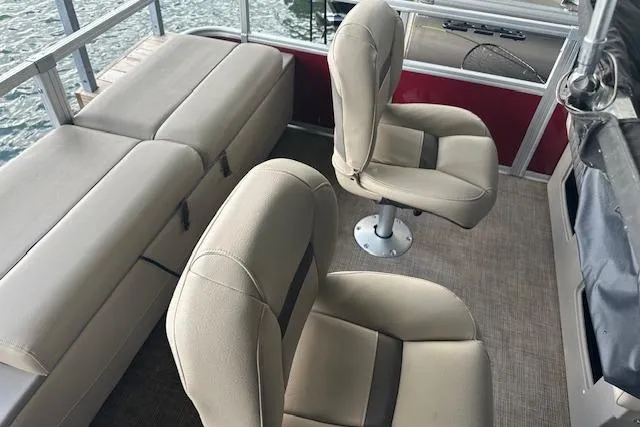 Slide: The Image of 2022 Sun Tracker Fishin' Barge 24 DLX interior with beige seating and red accents. - 7