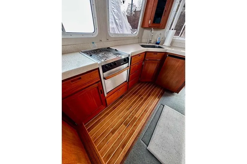 Slide: The Image of Kitchen area of a 2006 Nordic Tug 37 with wooden cabinets and stainless steel appliances. - 24
