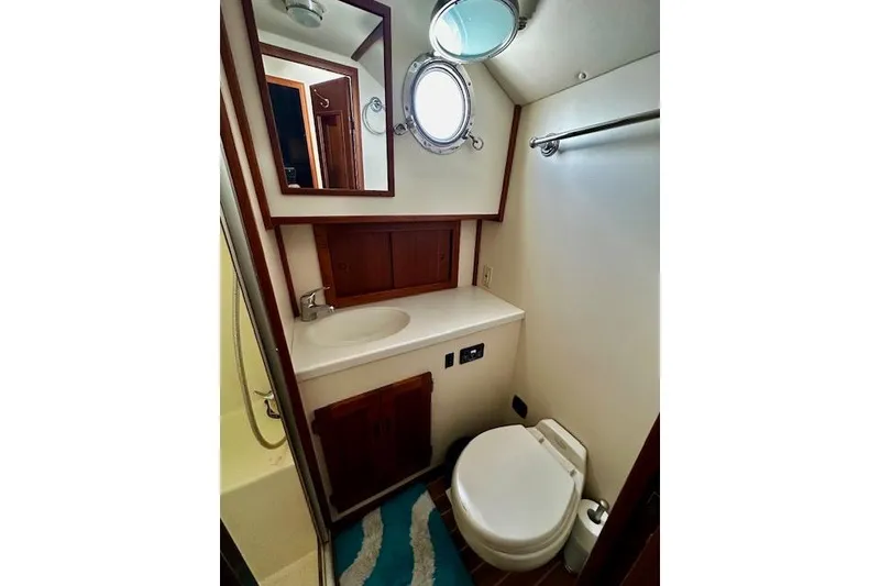 Slide: The Image of Bathroom interior of a 2006 Nordic Tug 37 boat, featuring a sink, toilet, and porthole. - 33