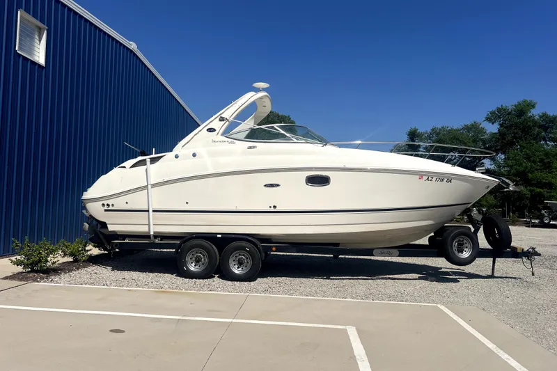The Image of 2011 Sea Ray Sundancer 280 boat on trailer, parked beside a blue building. - 0