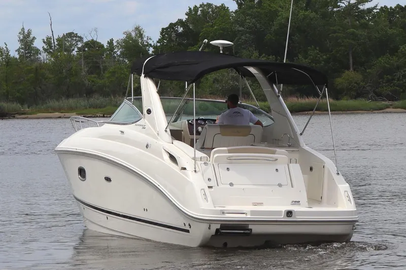 Slide: The Image of 2011 Sea Ray Sundancer 280 boat on trailer, parked outdoors with trees in background. - 10