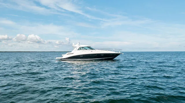 Slide: The Image of 2011 Sea Ray Sundancer 280 boat on trailer, parked near blue building. - 2