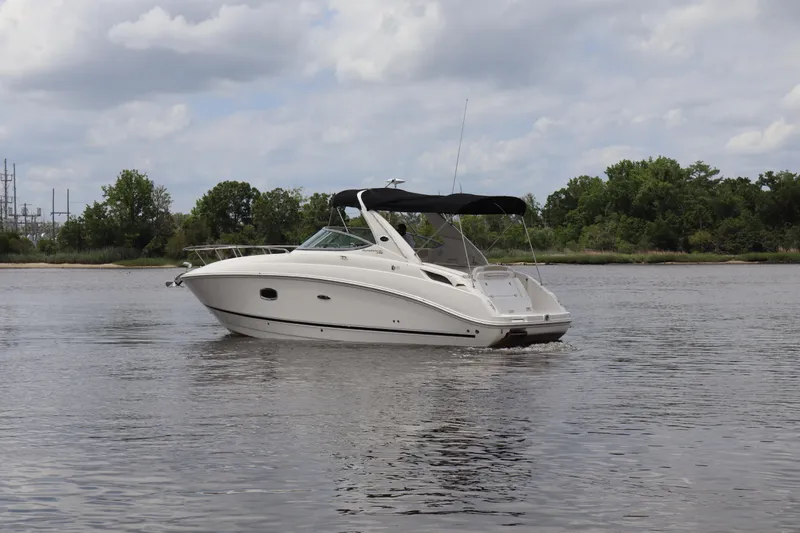 Slide: The Image of 2011 Sea Ray Sundancer 280 boat cruising on a calm river under a cloudy sky. - 48