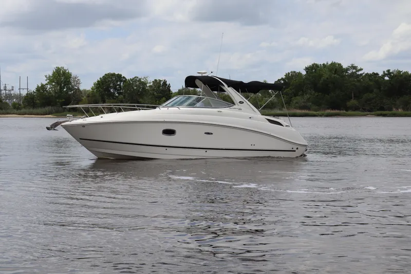Slide: The Image of 2011 Sea Ray Sundancer 280 cruising on a calm river with lush green trees in the background. - 55