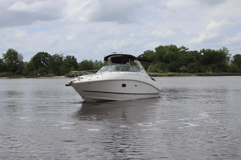 Slide: The Image of 2011 Sea Ray Sundancer 280 boat on calm water with lush green shoreline. - 59