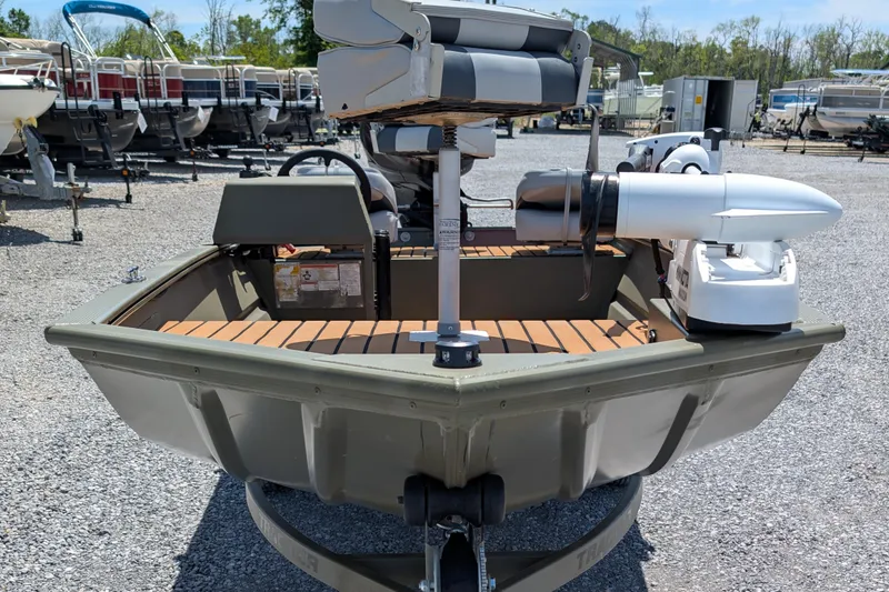 Slide: The Image of 2014 Bass Tracker boat with wooden deck, parked among other boats in a gravel lot. - 2