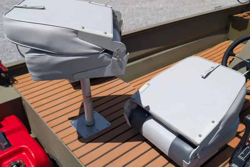 Slide: The Image of 2014 Bass Tracker boat seats on wooden deck, featuring gray upholstery and metal fixtures. - 8
