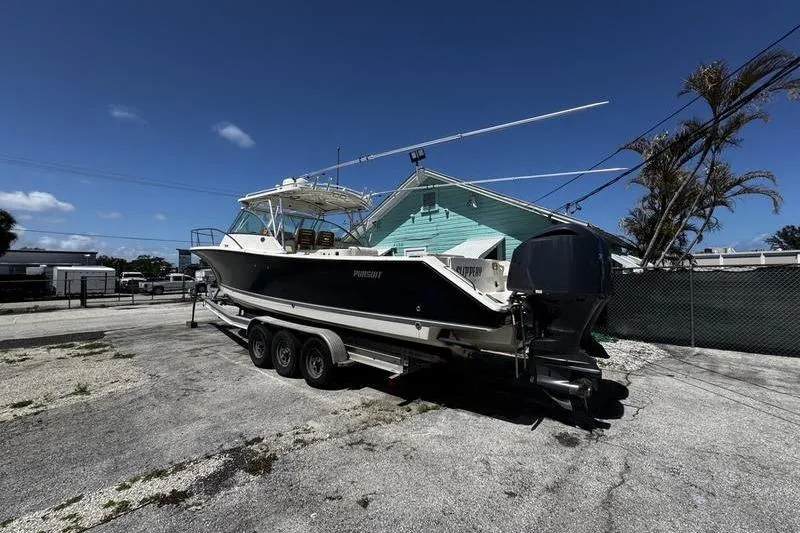 Slide: The Image of 2009 Pursuit 345 Drummond Runner LS boat on trailer, parked outdoors under clear sky. - 3