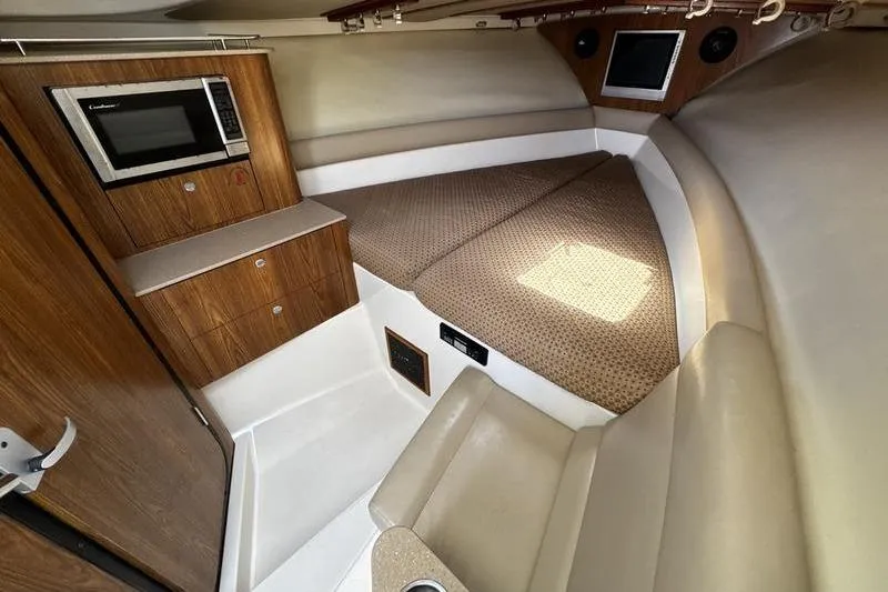 Slide: The Image of Interior of 2009 Pursuit 345 Drummond Runner LS with bed, microwave, and wood cabinetry. - 36
