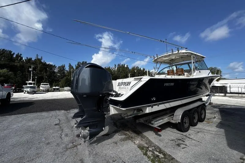 Slide: The Image of 2009 Pursuit 345 Drummond Runner LS boat on trailer, parked outdoors under blue sky. - 4