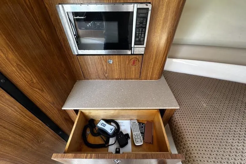 Slide: The Image of 2009 Pursuit 345 Drummond Runner LS interior with microwave and open drawer containing accessories. - 48