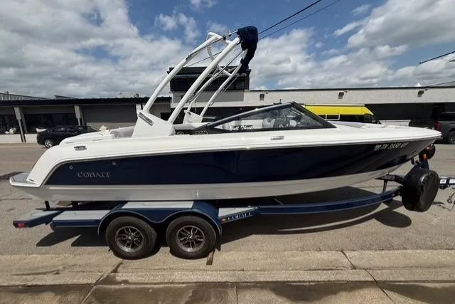 Slide: The Image of 2024 Cobalt CS22 boat on trailer, parked outdoors under a cloudy sky. - 2