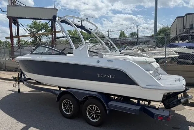 Slide: The Image of 2024 Cobalt CS22 boat on trailer, parked outdoors under a partly cloudy sky. - 5