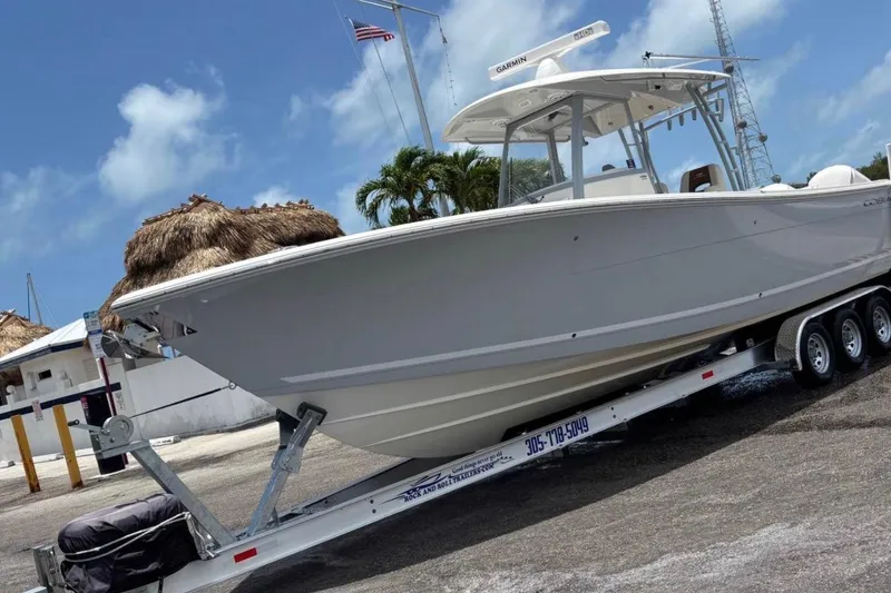 The Image of 2021 Cobia 320 Center Console boat on trailer, parked outdoors under blue sky. - 1