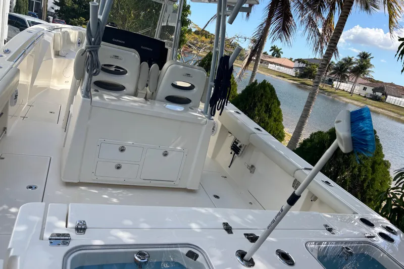 Slide: The Image of 2021 Cobia 320 Center Console boat interior with seating and storage, near a waterfront. - 11