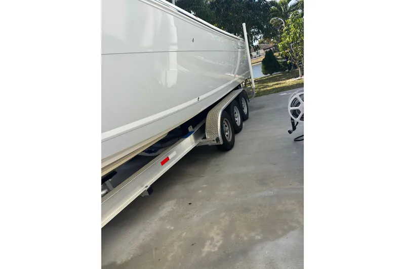 Slide: The Image of 2021 Cobia 320 Center Console boat on a triple-axle trailer in a driveway. - 13