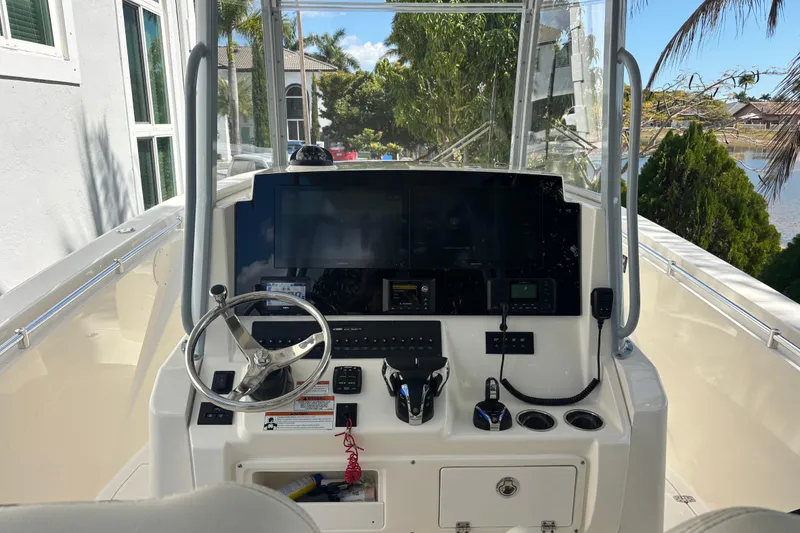 Slide: The Image of 2021 Cobia 320 Center Console boat helm with steering wheel and navigation controls. - 7