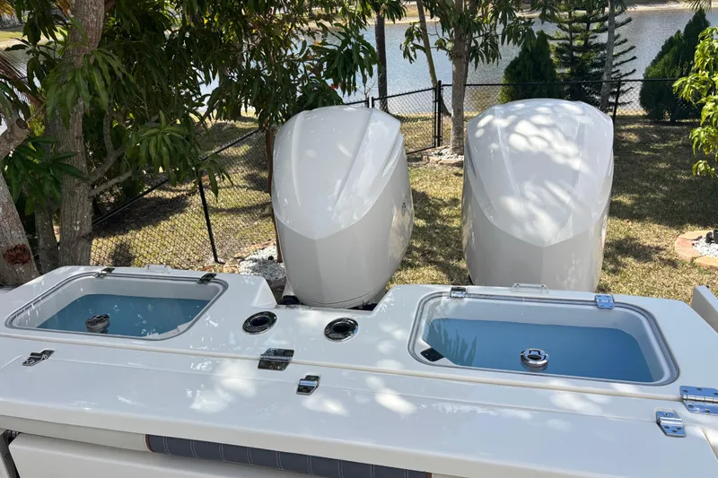 Slide: The Image of 2021 Cobia 320 Center Console boat with dual engines and live wells, docked near trees. - 8