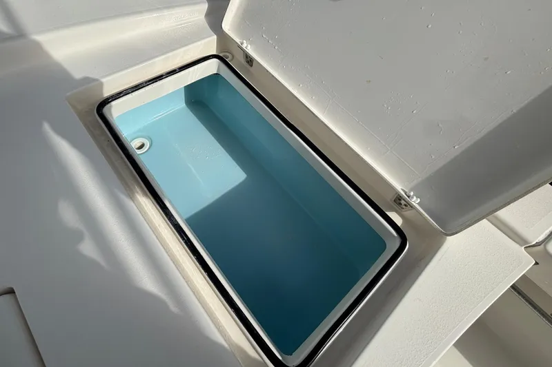 Slide: The Image of Open storage compartment on 2023 Pathfinder 2300 HPS boat, featuring a light blue interior. - 16